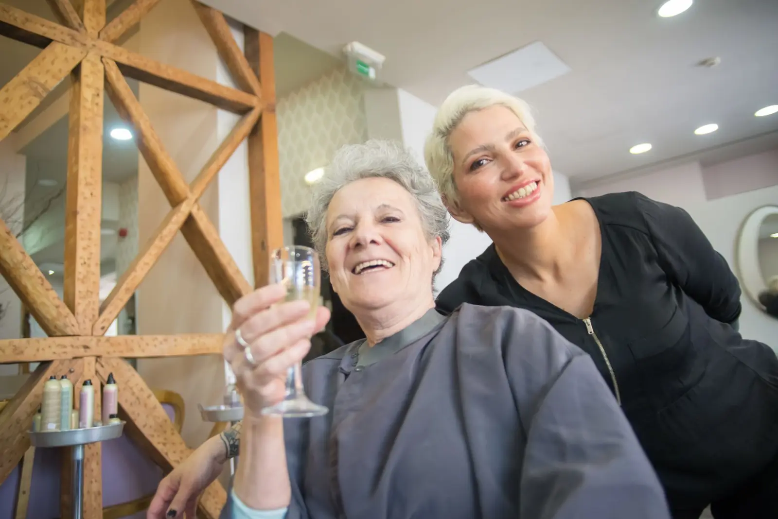 Coafor profesionist cu clientă, atmosferă caldă de salon